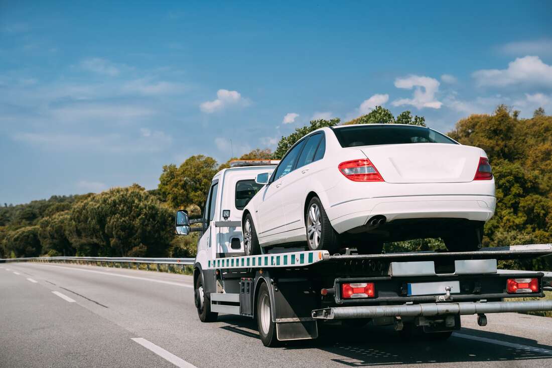 White car on flatbed tow truck