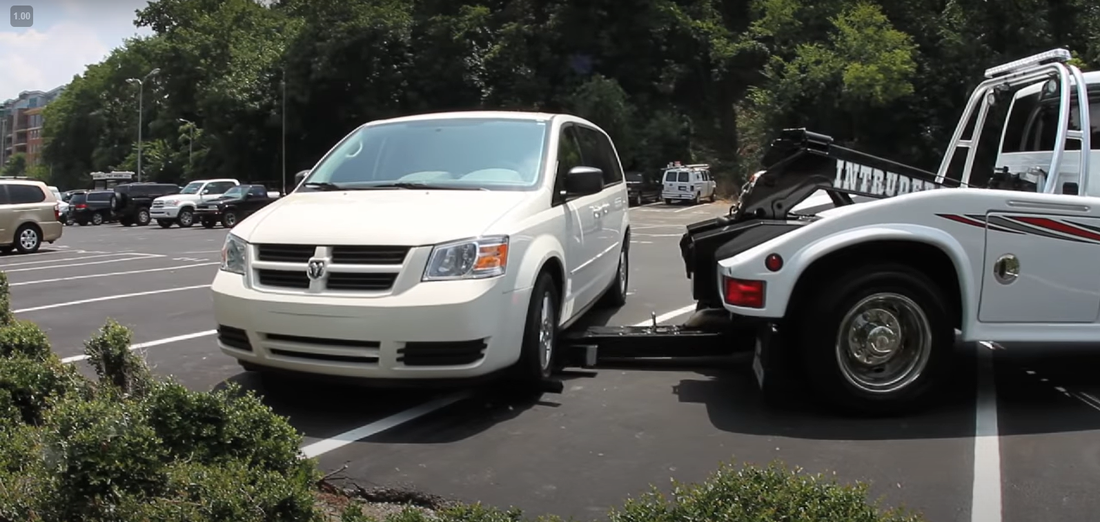 White mini van being towed sideways using a special tow truck