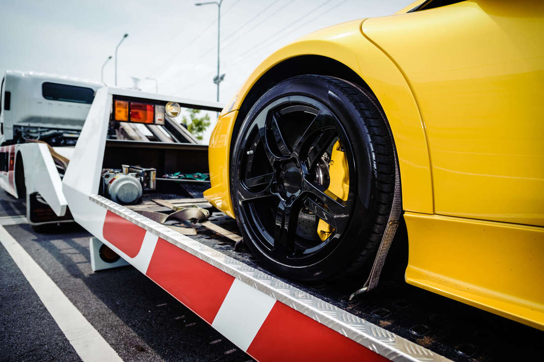 Yellow sports car on flatbed tow truck